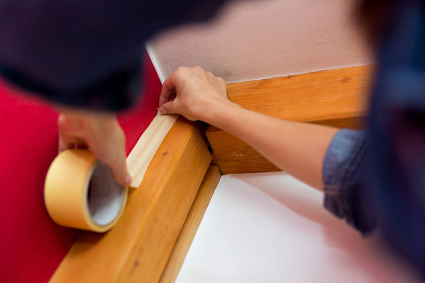 istock Home improvement. Women taping paint adhesive tape 1033697704