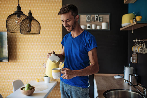 istock Smiling young businessman making morning coffee at home 1033706482