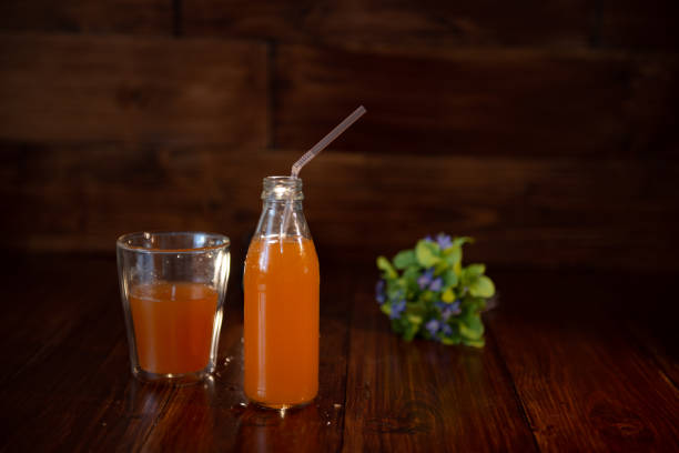 istock vintage bottle with juice, straw and flowers on wooden table 1033706708