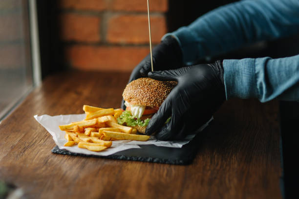 istock Man in black gloves takes a burger in his hands 1033716066