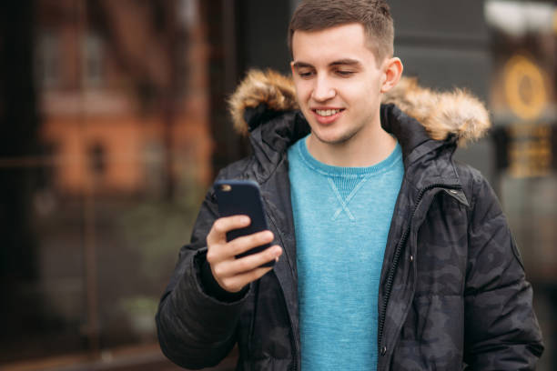 istock Man in a gray jacket is standing outside and using a phone 1033716874