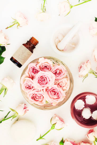 istock Rose essential oil extract top view pink petals bowls & bottles white table 1033723910