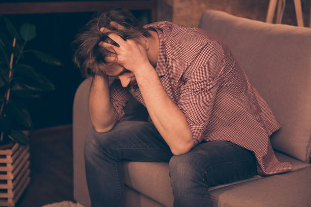 istock Frustrated young guy with bristle is holding his head, he is upset because his business has failed, sitting on the couch alone, bad luck, relationship problems, suffering from headache 1033726104