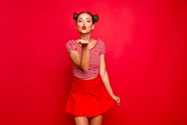 Cute girl send a kiss for you! Adorable young girl with nice make up wearing striped tshirt and red skirt isolated on bright background and sends air kiss from open palm Cute girl send a kiss for you! Adorable young girl with nice make up wearing striped tshirt and red skirt isolated on bright background and sends air kiss from open palm blowing a kiss stock pictures, royalty-free photos & images