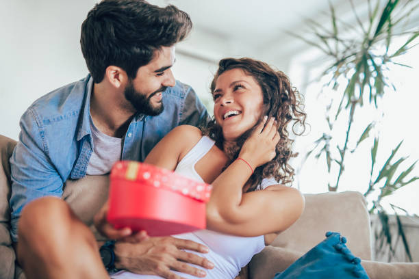 istock Smiling man surprises his girlfriend with present at home 1033740528