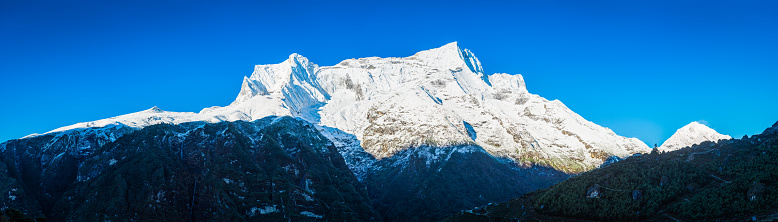 Snow capped Himalaya mountain peaks above the traditional teahouses and prayer flags of Namche Bazaar, the iconic Sherpa village and trading post deep in the Sagarmatha National Park, a UNESCO World Heritage Site, Nepal.