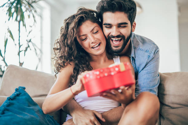 istock Smiling man surprises his girlfriend with present at home 1033743772