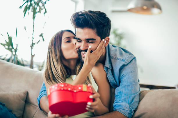 istock Smiling man surprises his girlfriend with present at home 1033744052