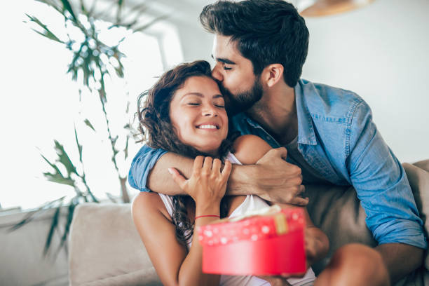 istock Smiling man surprises his girlfriend with present at home 1033746312