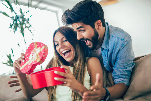 istock Smiling man surprises his girlfriend with present at home 1033747136