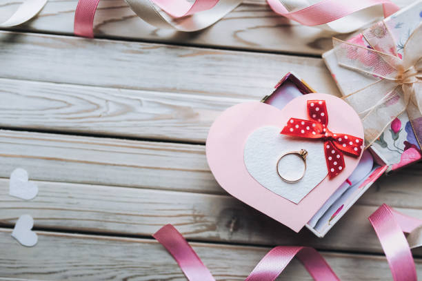 istock Marriage proposal concept. A wedding ring on a gift box on a wooden background. Valentine's Day. Copy space. Top view. 1033747464