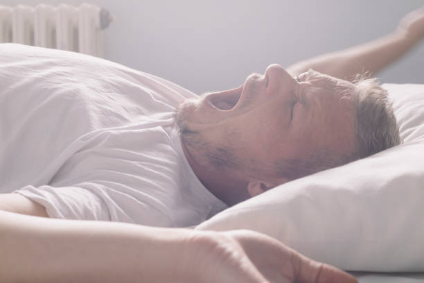 przystojny dorosły mężczyzna budzi się rano, leżąc na plecach, ziewając i rozciągając - pillow wake up yawning sleeping zdjęcia i obrazy z banku zdjęć