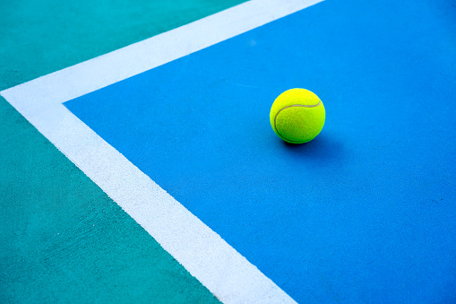 Top view on tennis ball on hard modern blue court near white line