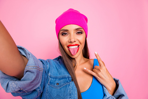 Close up photo portrait of beautiful nice glad cheerful careless teenager making selfie showing metal sign symbol isolated pastel girlish trendy background