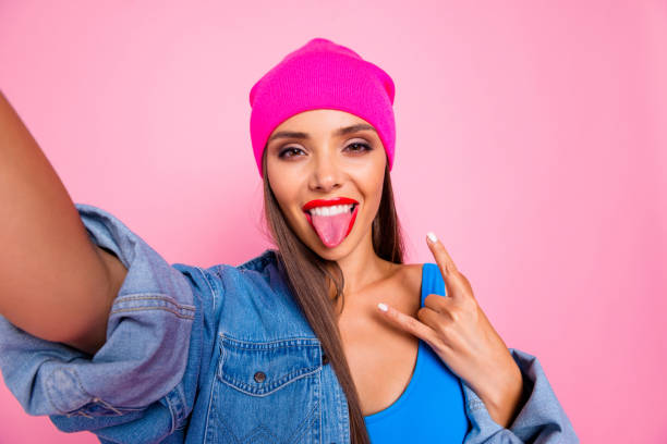 close up photo portrait of beautiful nice glad cheerful careless teenager making selfie showing metal sign symbol isolated pastel girlish trendy background - shirt women pink jeans imagens e fotografias de stock