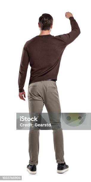 カジュアル セーターでフィット男は彼の前で何かを保持しているかのように持ち上げ片方の腕で後ろ姿で立っています - 後ろ姿のストックフォトや画像を多数ご用意