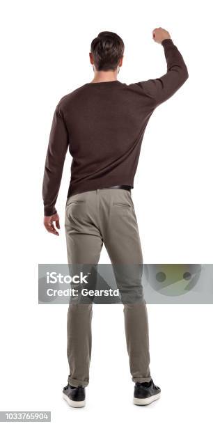 A Fit Man In Casual Sweater Stands In A Back View With One Arm Lifted Up As If Holding Something In Front Of Him Stock Photo - Download Image Now