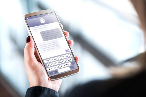 istock Woman sending text messages with mobile phone. Cellphone in hand with sms application on screen. Person using instant messaging software with smartphone. 1033774466