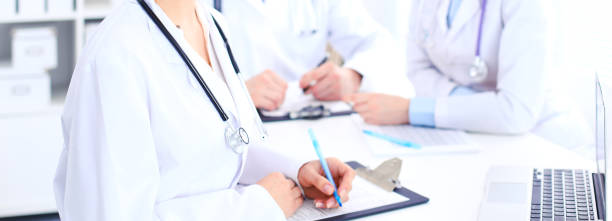 istock Group of unknown doctors working at hospital while sitting at the table. Teamwork and success concept in medicine. 1033774576