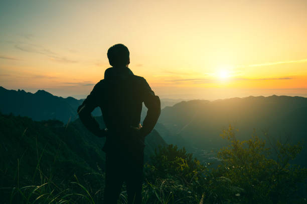 istock Man's silhouette on mountains looking sunset 1033786874