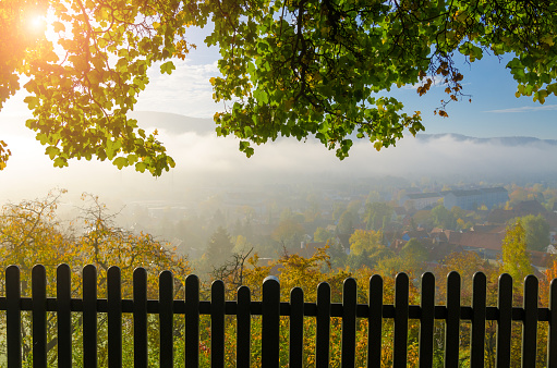 Morning fog over village in germany - autumn colors and fence shadow