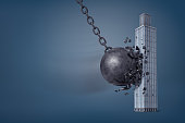 3d rendering of giant iron wrecking ball breaks in pieces when it hits a business skyscraper.
