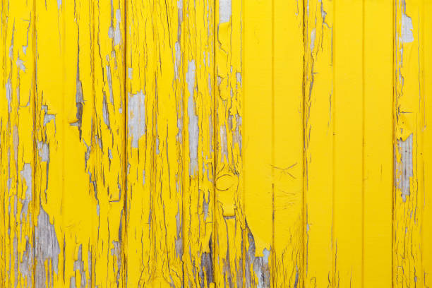 Vertical background of the old wooden planks with cracked yellow paint