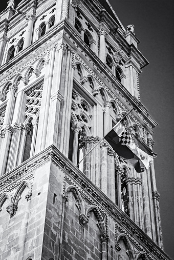 Detail of Cathedral of St. Lawrence with croatian flag in Trogir, Croatia. Religious architecture. Travel destination. Black and white photo.