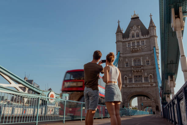 カップルは、タワー ブリッジ、ロンドンの赤い 2 階建てバスの写真を撮る - tower bridge uk london england people ストックフォトと画像