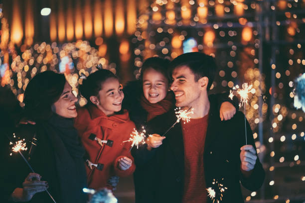 família feliz no natal com queima de fogos - adult couple four people urban scene - fotografias e filmes do acervo