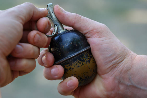 The hand holds an old Soviet grenade on pink background. Closeup photo