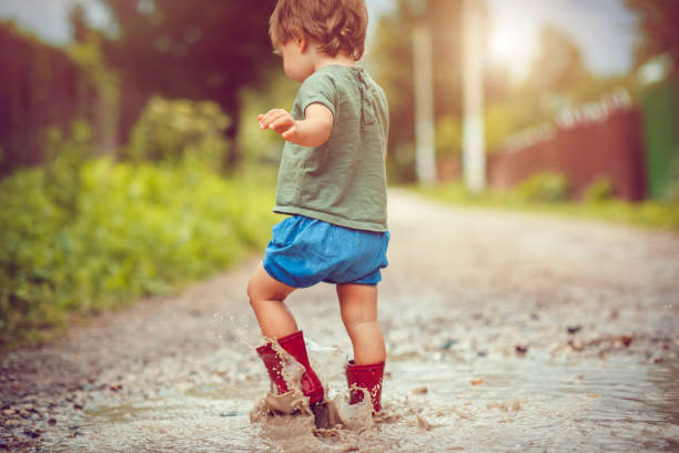 istock Little boy playing in puddle, rear view 1033851264