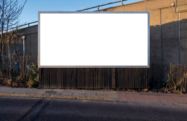 Blank billboard for customisation in an urban location Billboard blank near road and pavement for customisation. Outdoor landscape rectangular advertising display for insertion of creative designed content billboard stock pictures, royalty-free photos & images