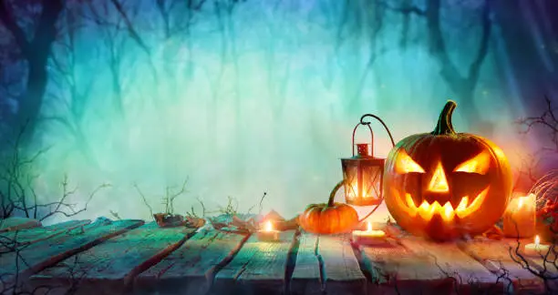 Pumpkin And Candles On Wooden Table In Misty Night