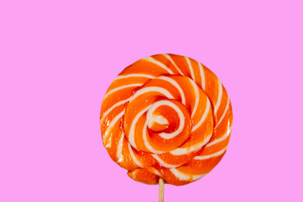 Sweet orange lollipop on pink background