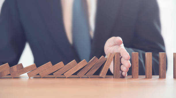 istock Problem Solving, Close up hand of businessman stopping falling blocks on table. 1033886960