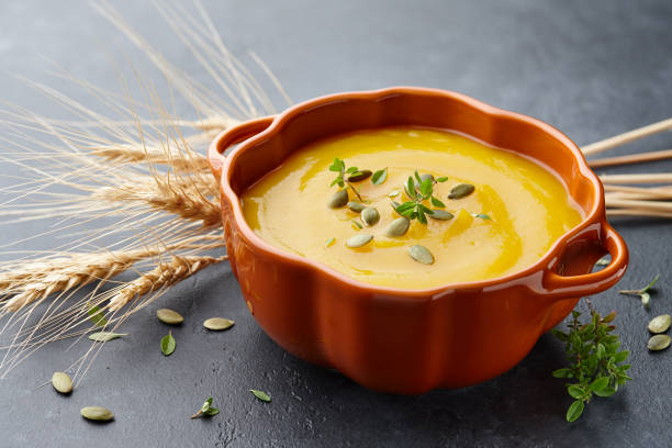 istock Pumpkin soup with thyme and pumpkin seeds on black background 1033905692