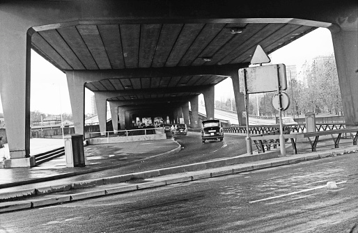 Taxi travelling along Harrow Road as it passes under the massive concrete Westway flyover. London, October 3rd, 1986.