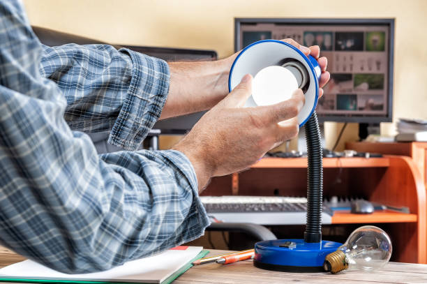 istock Electrician technician at work installs the new energy-saving LED bulb. 1033906380