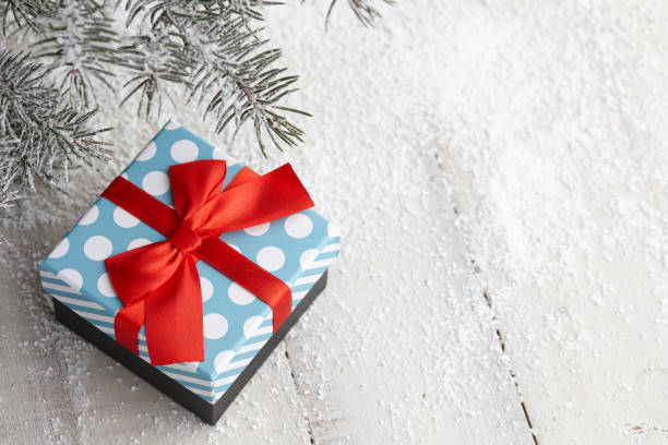 istock Christmas gift box with red ribbon bow under snowy fir tree 1033918782
