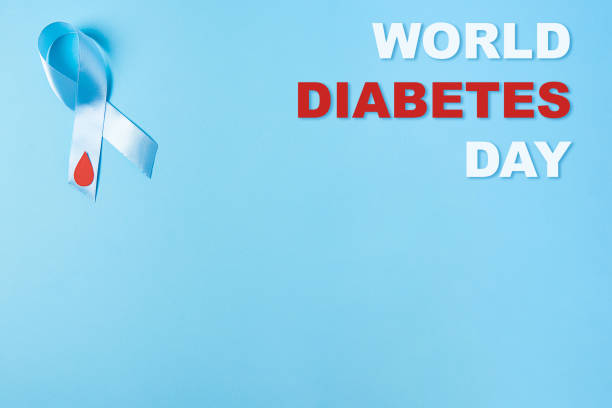 inscription world diabetes day and blue ribbon awareness with red blood drop on a blue background stock photo