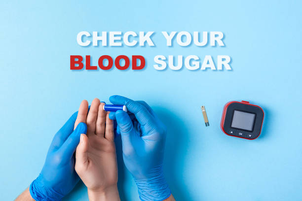 inscription check your blood sugar and Nurse making a blood test with lancet. Man's hand with red blood drop with Blood glucose test strip and Glucose meter stock photo