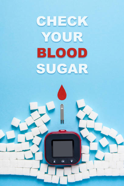 inscription check your blood sugar and red blood drop and wall made of sugar cubes ruined by Blood glucose test strips and Glucose meter on blue background stock photo