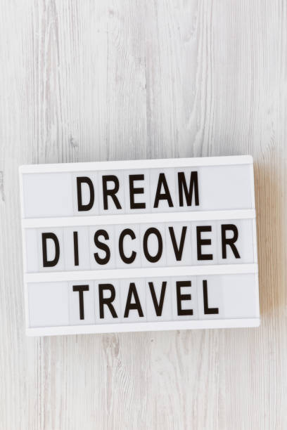 istock Modern board with text 'Dream Discover Travel' word on white wooden surface, overhead view. From above, flat lay, top view. 1033924716