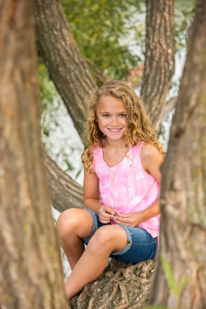 istock Young Girl Smiling at Camera From Tree on Riverbank 1033924722