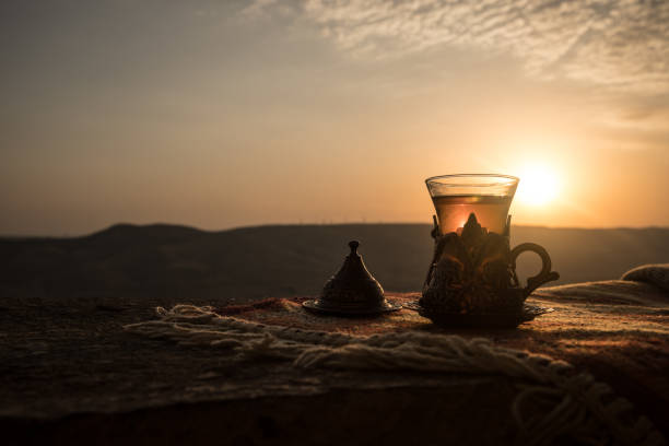 istock Arabian tea in glass on a eastern carpet. Eastern tea concept. Armudu traditional cup. Sunset background. Selective focus 1033930966