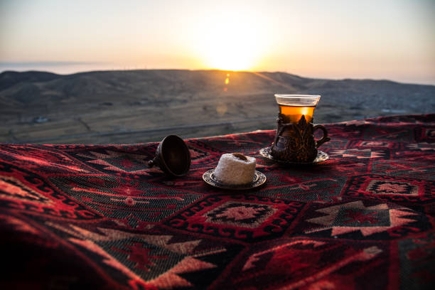 istock Eastern black tea in glass on a eastern carpet. Eastern tea concept. Armudu traditional cup. Sunset background. 1033931012