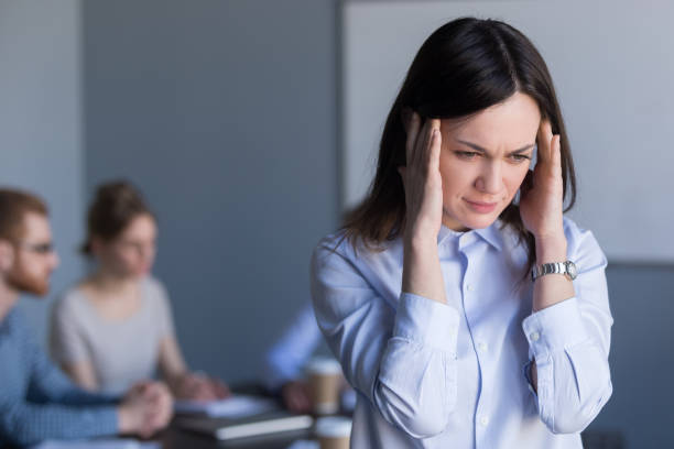 подчеркнутая работница страдает от головной боли во время встречи в офисе - banging your head against a wall audio стоковые фото и изображения