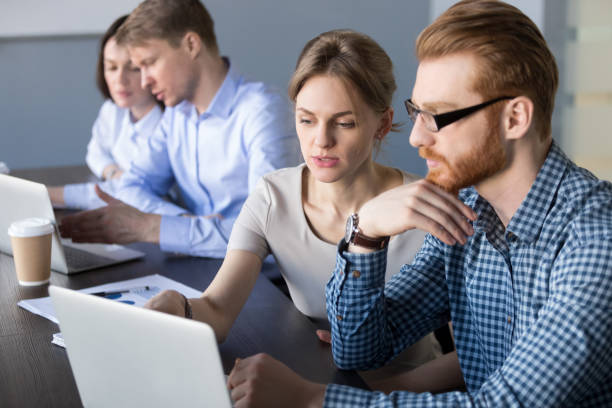 istock Concentrated workers busy at laptops discussing business projects 1033950732