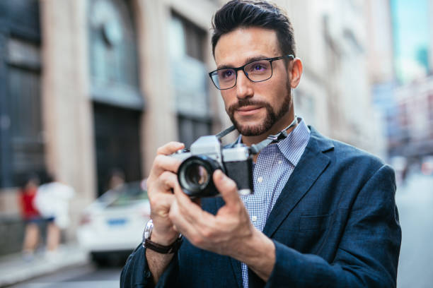 Man photographer holding digital camera and taking photos outdoors
